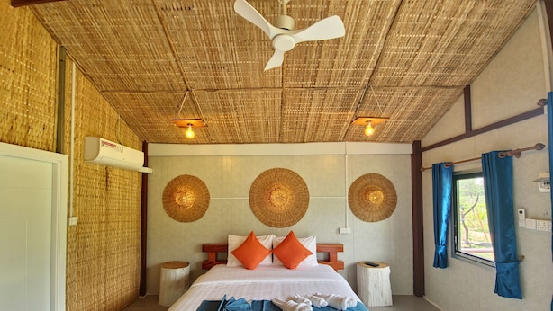 A room with a bed, a ceiling fan, wall-mounted lights, and a window with curtains.