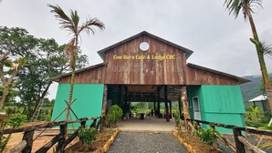 A rustic building labeled 'Cow Barn Café & Lodge CBC' with a covered entrance and outdoor seating area.