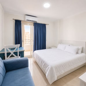 A hotel room with a bed, a desk, a chair, and a view through a door. - Cozy Studio with FREE Private Beach Access in Tiba Golden Resort (Hurghada)