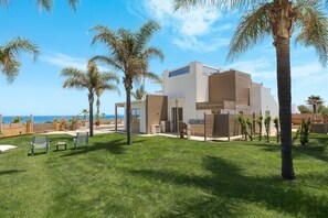 Ein modernes Haus mit Pool, Palmen und Meerblick.