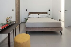 Une chambre à coucher avec un lit, des tables de chevet, un bureau et un pouf jaune.