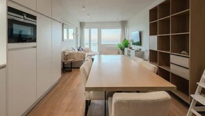 Una cocina moderna con comedor, armarios empotrados, un ventanal grande y un televisor.