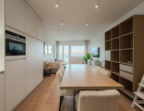 Eine moderne Küche mit Essbereich, eingebauten Schränken, einem großen Fenster und einem Fernseher.