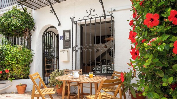 A patio with a wooden table and chairs, potted plants, and a metal gate. - Vacation home Carmen by Interhome (Nerja)