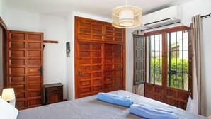 A bedroom with a large bed, wooden wardrobe, and a window with a view of greenery. - Vacation home Carmen by Interhome (Nerja)