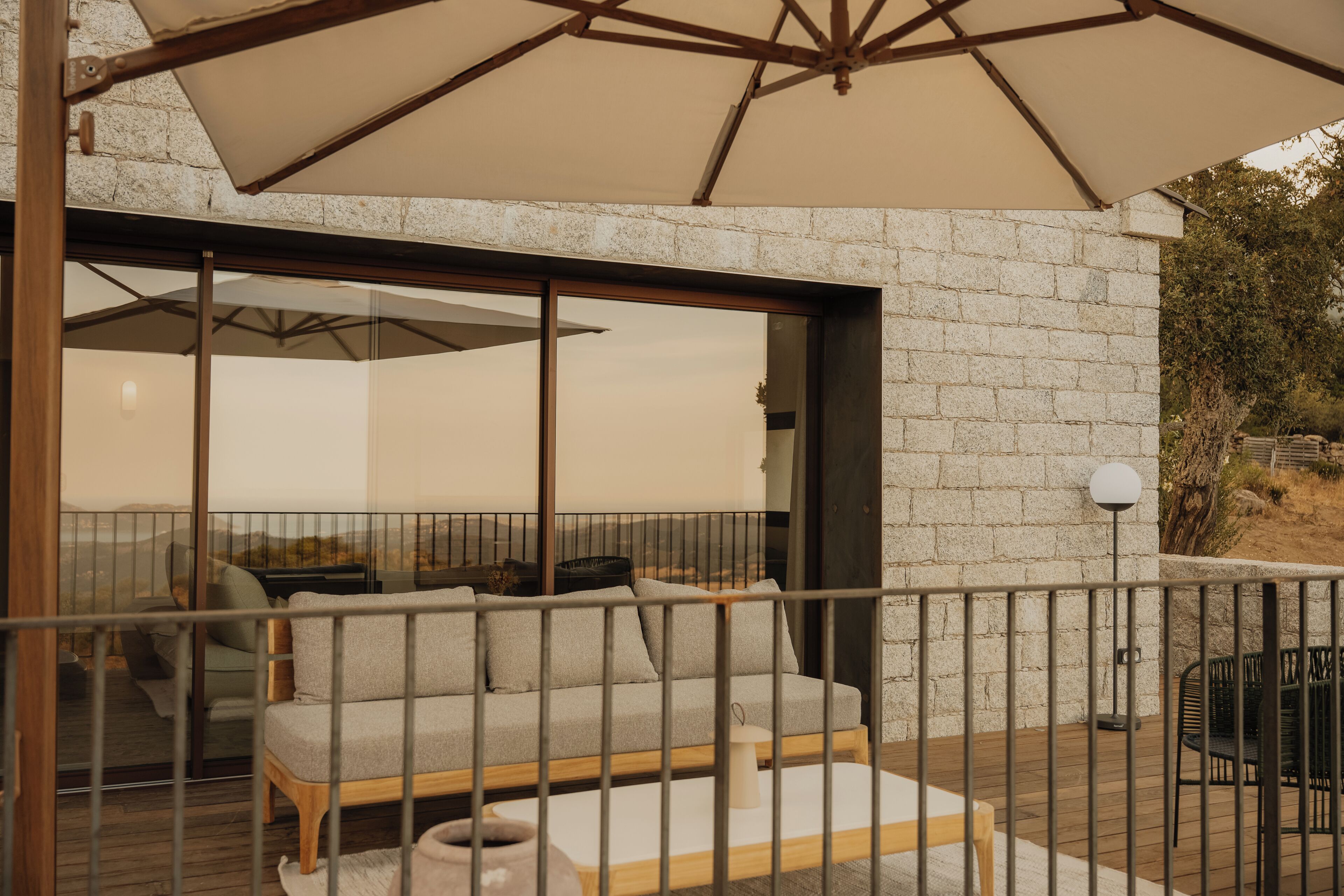 A balcony with a sofa, a table, and a large umbrella.