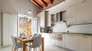 Uma cozinha moderna com área de jantar, parede de pedra e vigas de madeira no teto.