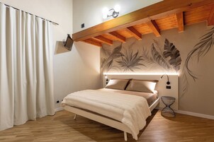 Un dormitorio con cama, televisor de pared, lámpara de techo y un mural decorativo.
