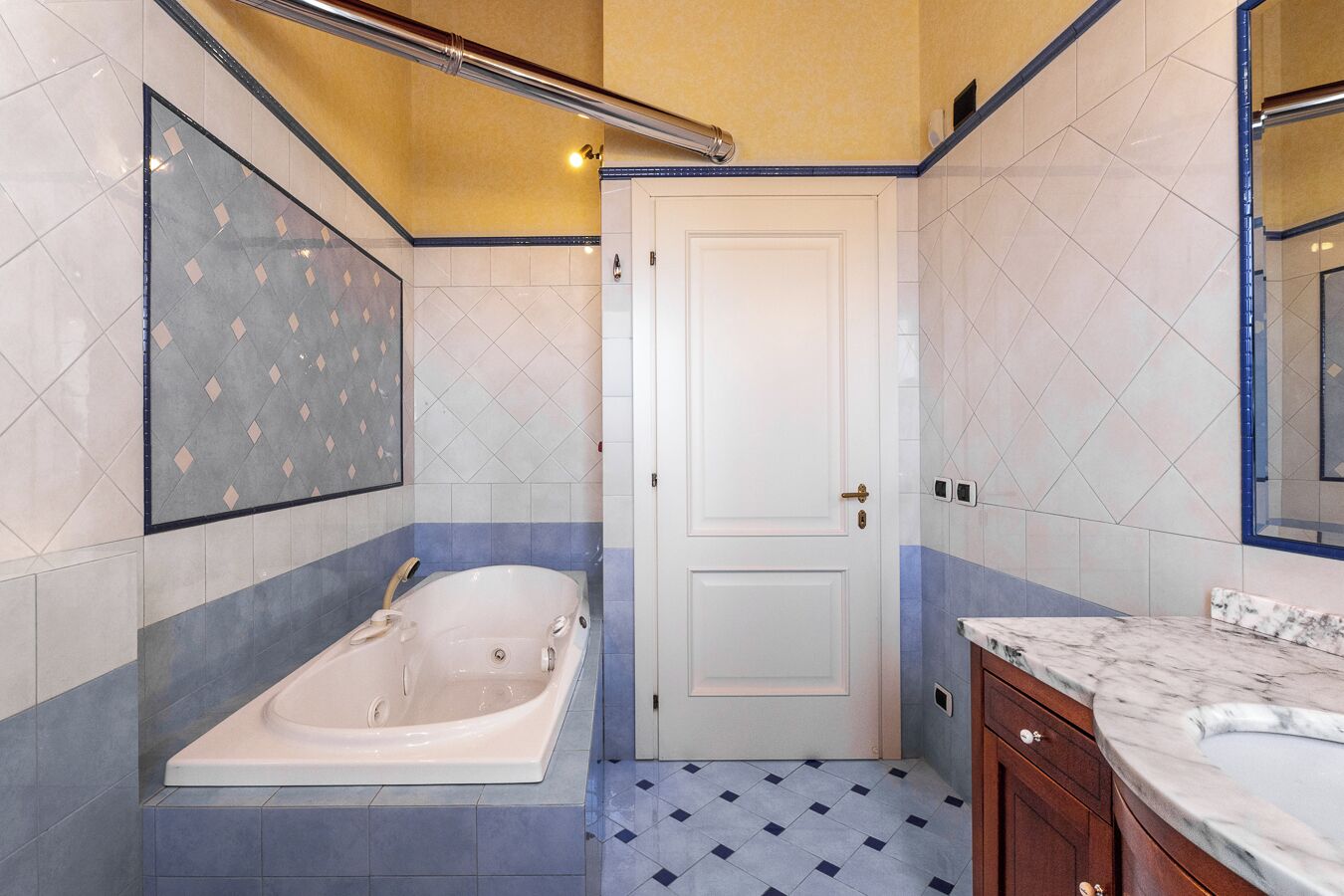 Ein Badezimmer mit einer Badewanne, einer weißen Tür und gefliesten Wänden.