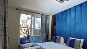Une chambre d’hôtel avec un lit, un bureau, une chaise et une vue sur les bâtiments environnants.