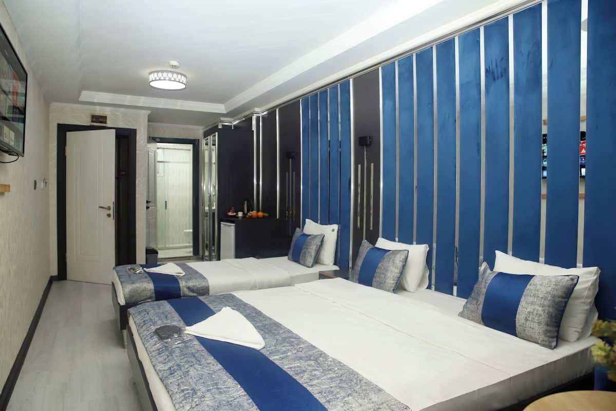 Quarto de hotel com duas camas, um espelho grande e um guarda-roupa com padrão listrado vertical.