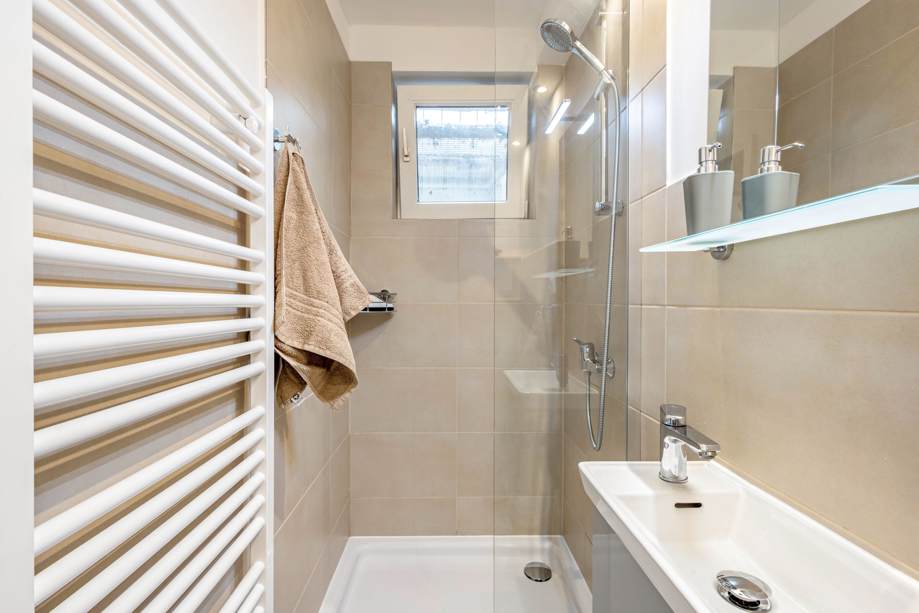 Ein modernes Badezimmer mit Duschkabine aus Glas, einer weißen Badewanne und einem Handtuchhalter mit Handtuch.