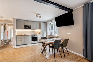 Eine moderne Küche mit Essbereich, Holzboden und einem an der Wand befestigten Flachbildfernseher.