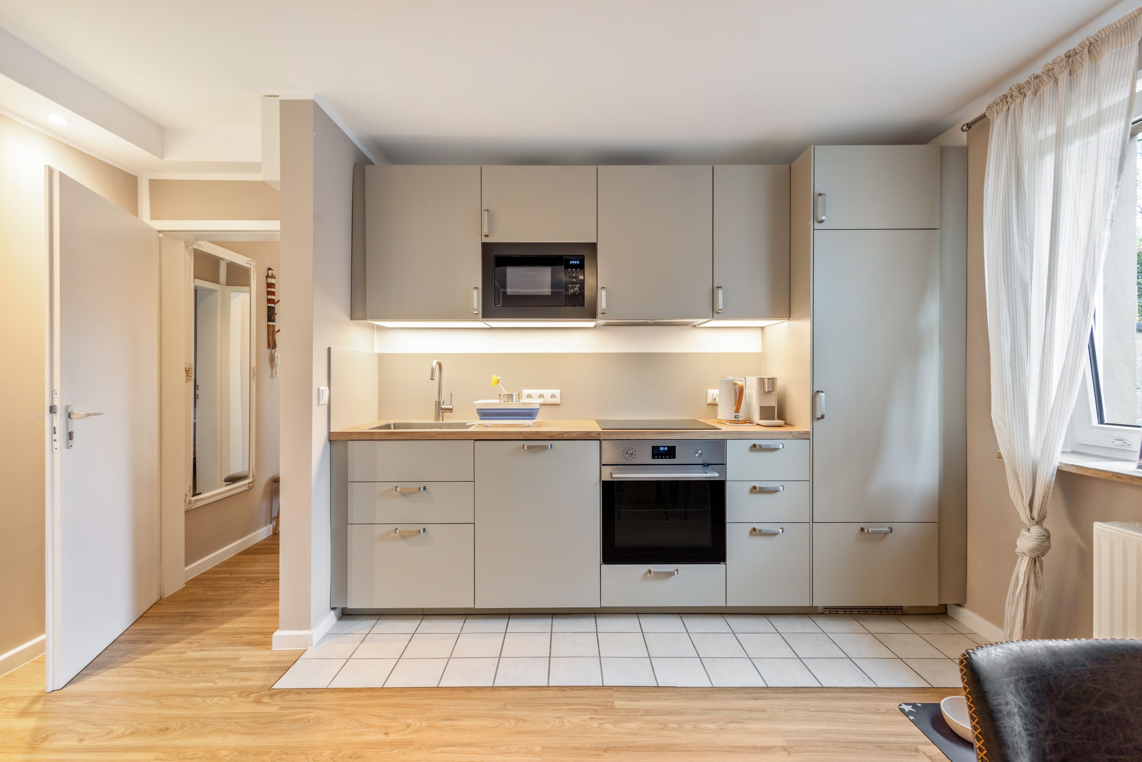 A modern kitchen with a built-in microwave, oven, and sink.