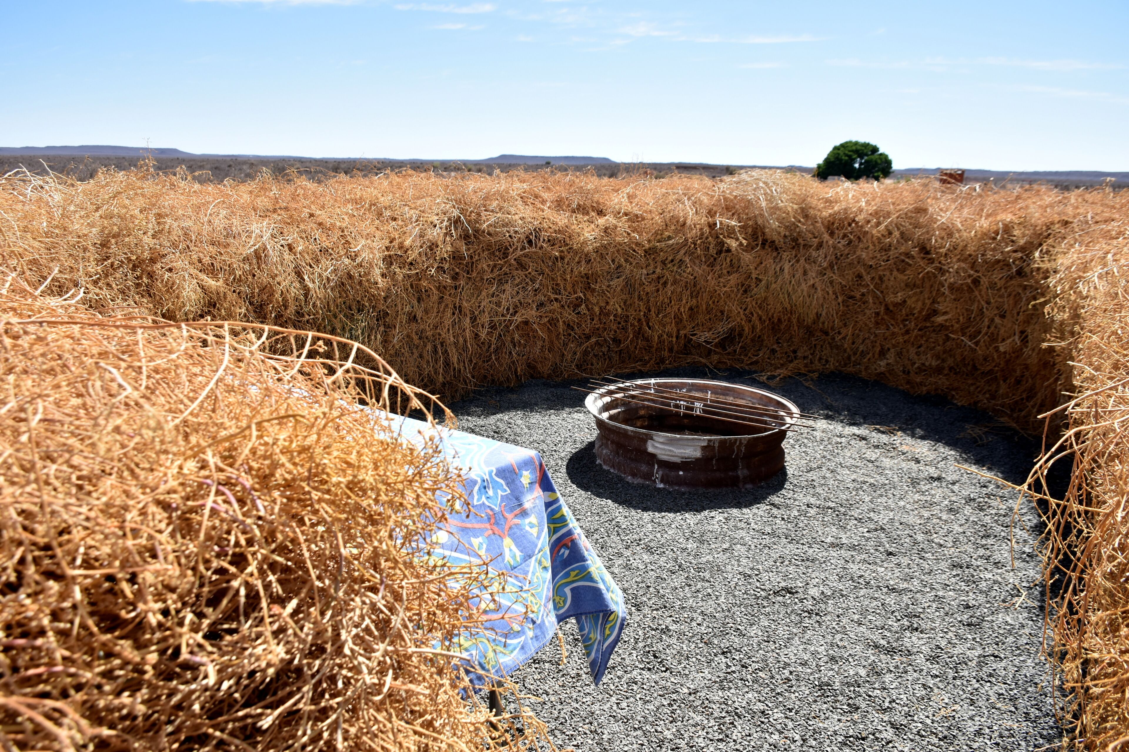 A rustic outdoor setting with hay bales, a metal barrel, and a table with a cloth.