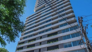 A tall, modern building with a glass entrance and a sign reading 'SKY TOWER.' - Corporate Stays Sky Tower - 807  (Asunción)