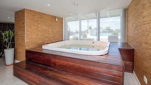 A modern bathroom with a wooden floor, a large bathtub, and a view of the outdoors. - Corporate Stays Sky Tower - 807  (Asunción)