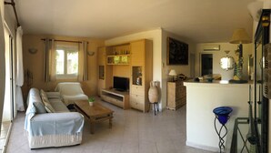 Een woonkamer met een bank, televisie, houten kast en een kleine tafel.