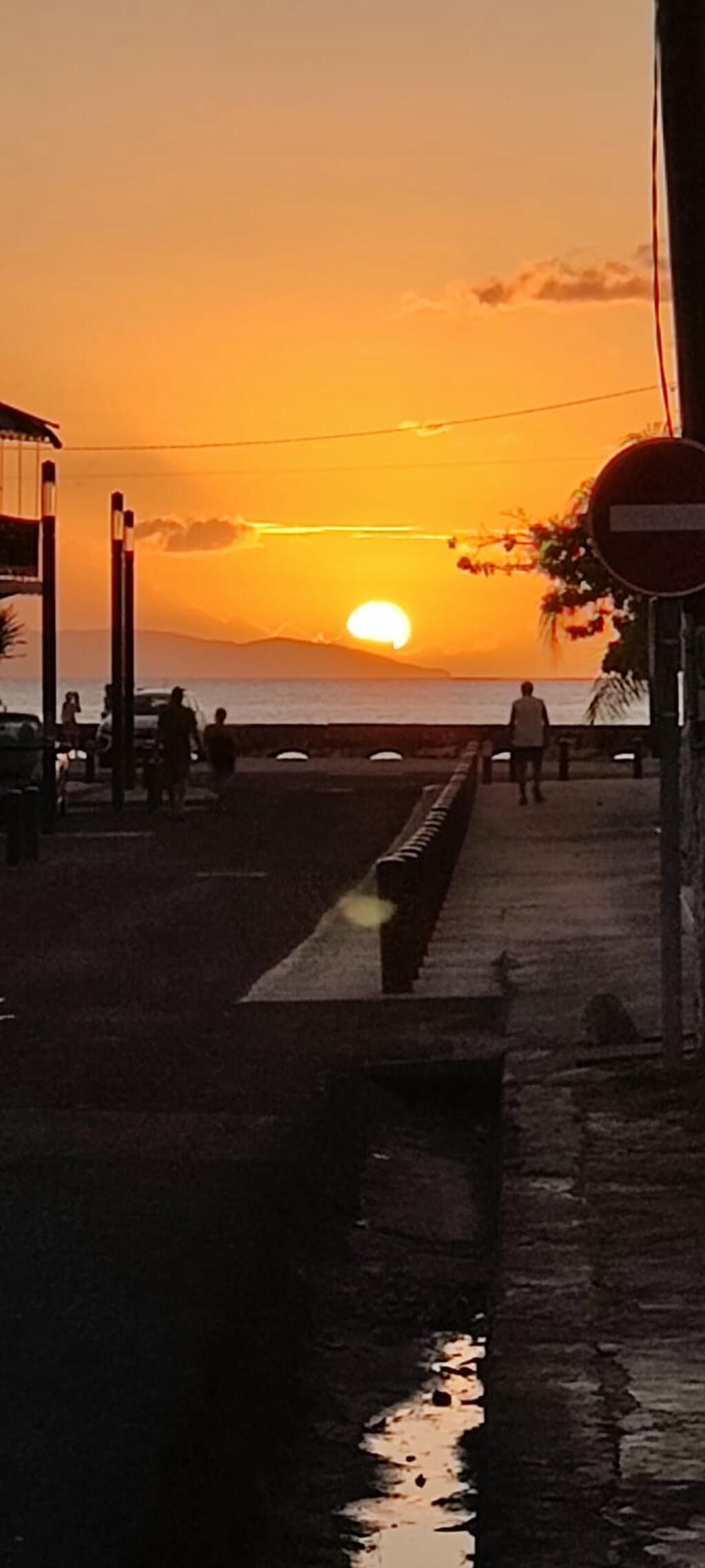 Un tramonto su uno specchio d'acqua con una passerella e un segnale di divieto di accesso.