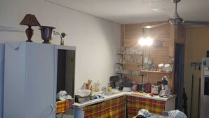 Ett kompakt kök med en köksö i mitten, ett kylskåp och en takfläkt.