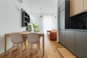A modern kitchen with a black stove, a dining table with chairs, and a sofa in the background. - A modern 53 sqm apartment, ideal for 4 people, located on the first floor of a building with an elevator.The property is situated in the charming Porta Romana district; the city center is easily accessible via various bus and tram lines, as well as the  (Milan)