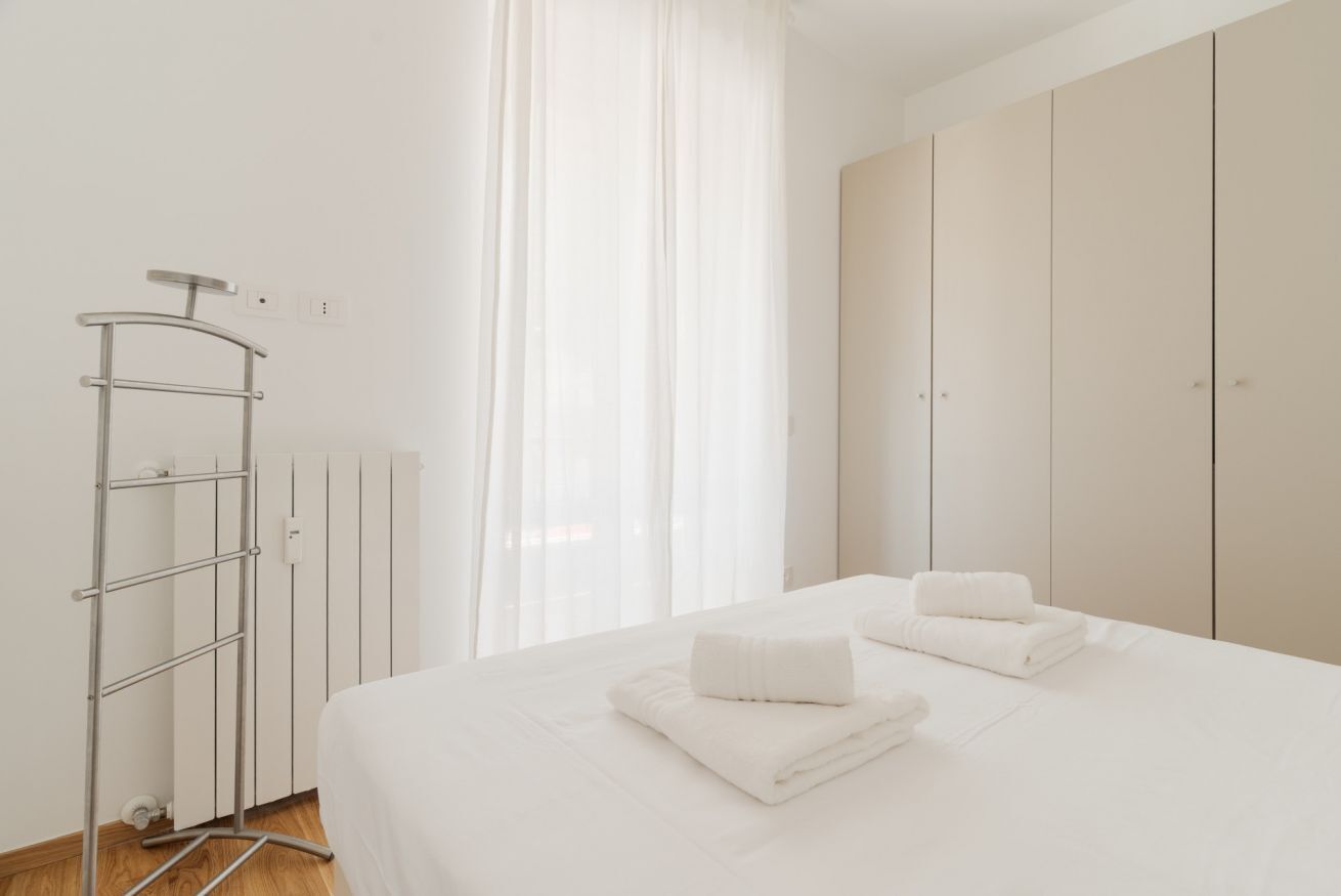Una camera d'albergo con un letto, un termosifone, un portasciugamani e un armadio.