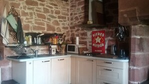 Et køkken med stenvæg, lyse skabe, en mikroovn, en vask og et skilt for Bieres Meteor.