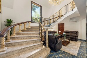 Eine prächtige Treppe mit aufwendiger Geländerarbeit, ein komfortables Ledersofa und ein Marmorboden.