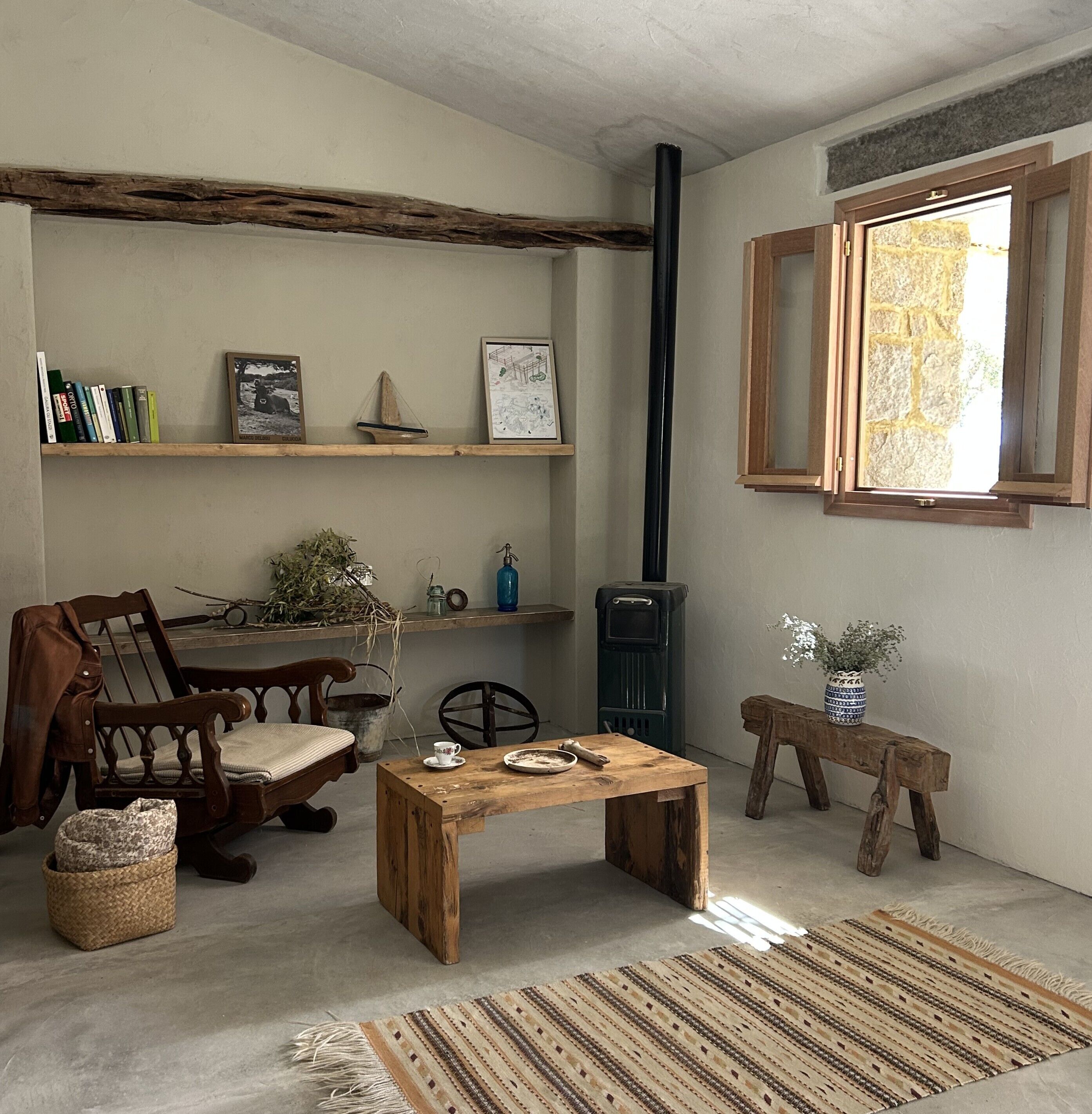 Een knus interieur met een houten tafel, stoelen, een boekenkast, een open haard en een raam.