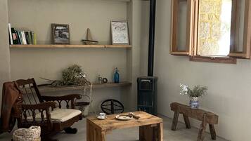 Een knus interieur met een houten tafel, stoelen, een boekenkast, een open haard en een raam.