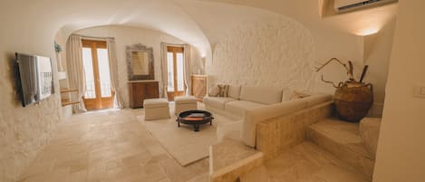 A spacious living area with a stone floor, a sofa, a coffee table, and a large vase.
