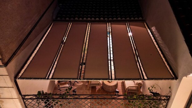 A balcony with a metal fence, a tiled roof, and outdoor furniture. - Elite Collection - Olea The Sun & Stone Terrace (olbia)