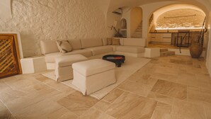 A spacious living area with a large L-shaped sofa, a coffee table, and a fireplace. - Elite Collection - Olea The Sun & Stone Terrace (olbia)