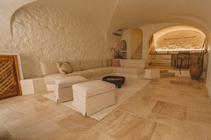 Uma sala de estar ampla com um sofá em formato de L, uma mesa de centro e uma lareira.