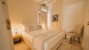 A bedroom with a bed, a chair, a painting, and a window with curtains. - Elite Collection - Olea The Sun & Stone Terrace (olbia)