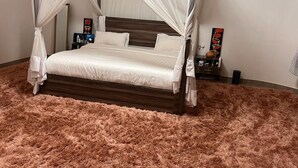 A four-poster canopy bed with a fluffy pink rug, wooden headboard, and bedside tables with decorative items. - 7-bedroom house in lovely Gacuriro for your stay (Kigali)