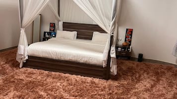 Un lit à baldaquin à quatre poteaux, agrémenté d’un tapis rose moelleux, d’une tête de lit en bois et de tables de chevet ornées d’objets décoratifs.
