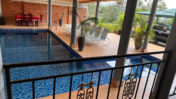 A swimming pool with a tiled deck, outdoor seating, and a covered patio area. - 7-bedroom house in lovely Gacuriro for your stay (Kigali)