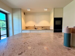Una cocina moderna con una amplia encimera de mármol, un lavamanos integrado y un horno.