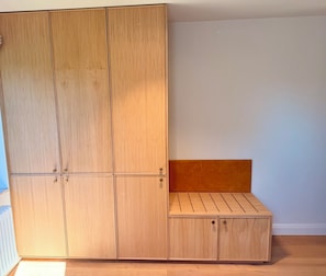 Una habitación con un armario de madera, un banco y un radiador.