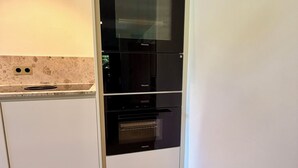 A kitchen with white cabinetry, a black oven, and a microwave. - New: High-End Design Lodge Surrounded by Nature – Teos im Wiedergut (Sternberg)