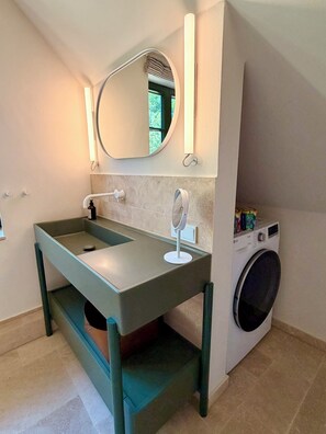 Ein Badezimmer mit Waschbecken, Spiegel und Waschmaschine.