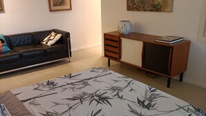 Un dormitorio con una cama, un sofá, un armario y un cuadro en la pared.
