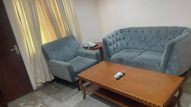 A living room with a sofa, a coffee table, a small side table, and a door. - Blissworld Hotel (Akure)
