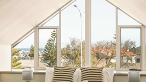 A bedroom with a large window, a bed with striped pillows, and a view of a marina.