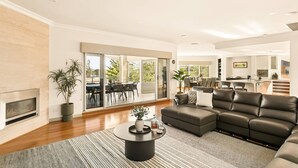 A modern living room with a fireplace, a sectional sofa, a coffee table, and a dining area with a large window.