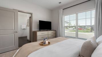 Une chambre d’hôtel avec un lit, une télévision, une fenêtre avec des stores et une porte donnant sur une salle de bain.