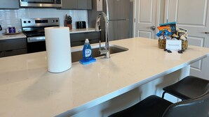 Een moderne keuken met roestvrijstalen apparatuur, een marmeren aanrechtblad en een welkomstbord.