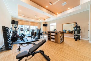 A well-lit gym with various exercise equipment, including treadmills, weight machines, and free weights.