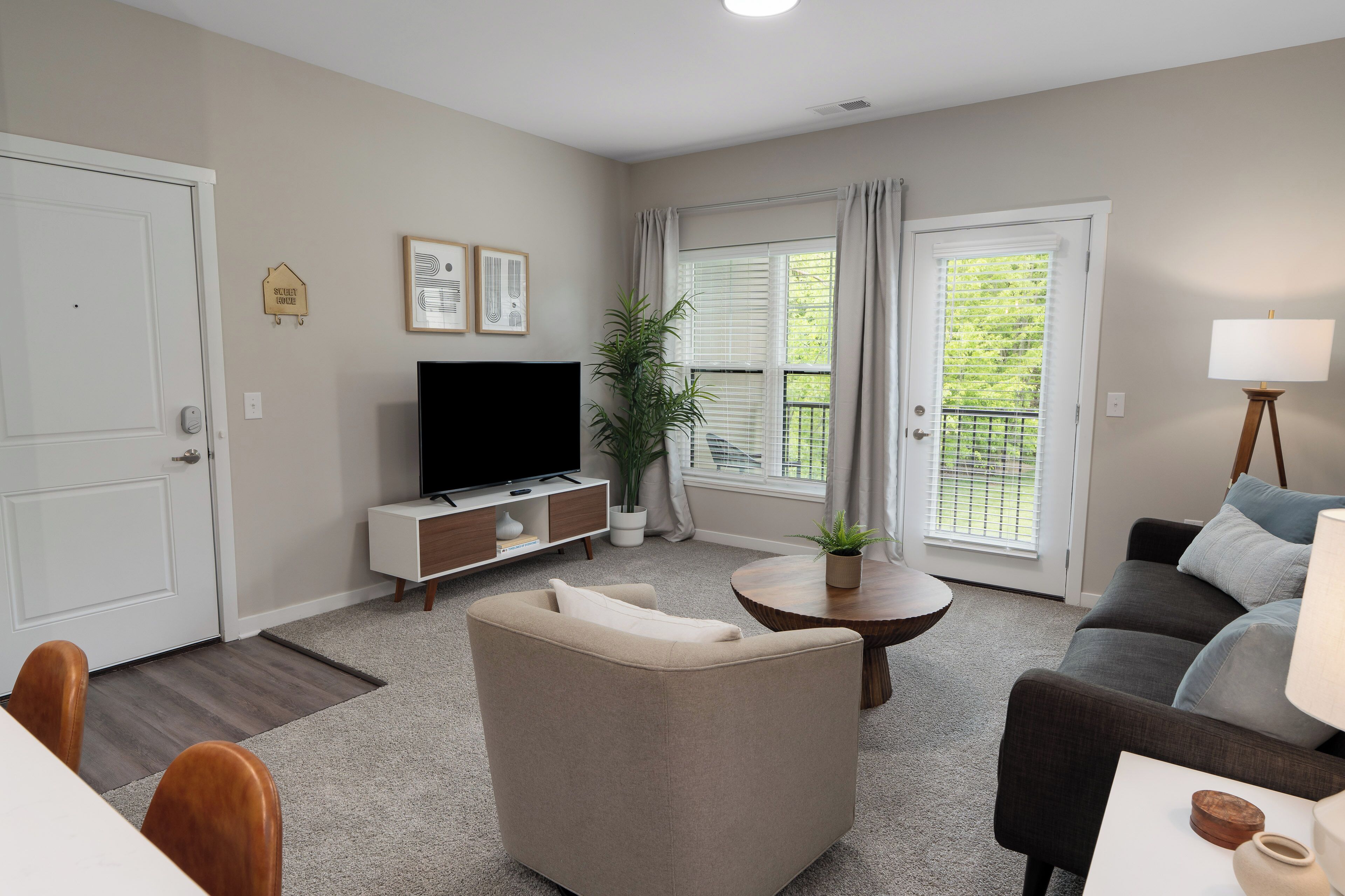 Ein Wohnzimmer mit einer Couch, einem Fernseher, einem Couchtisch und einem Essbereich mit Stühlen.